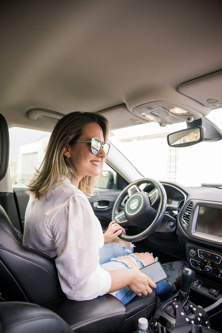 Aluna sorrindo ao volante durante uma aula de direção